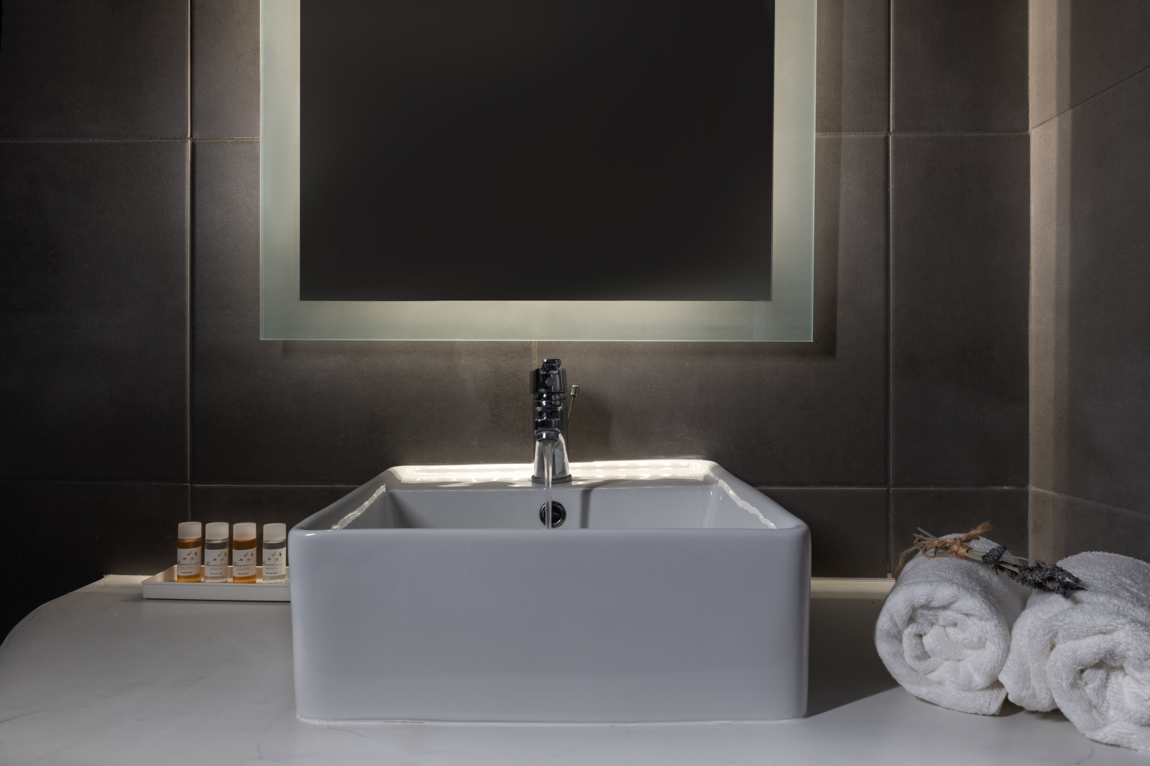 A bathroom with a white sink, a mirror above it, and a towel rack with towels.