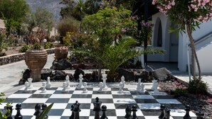 A chessboard set outdoors with a garden in the background. - Rivari Hotel (Santorini)