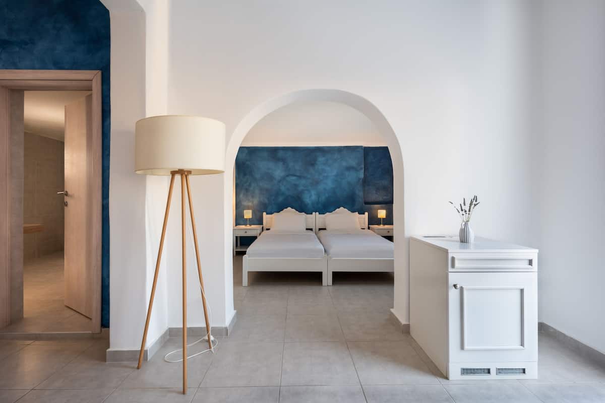 Un dormitorio moderno con una cama grande, una mesita de noche, una lámpara de pie y un armario.