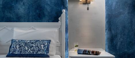 A bedroom with a bed, a nightstand, and a wall-mounted lamp.
