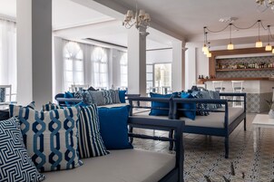 Ampla área de estar com sofás, almofadas estampadas e um bar com prateleiras cheias de garrafas.