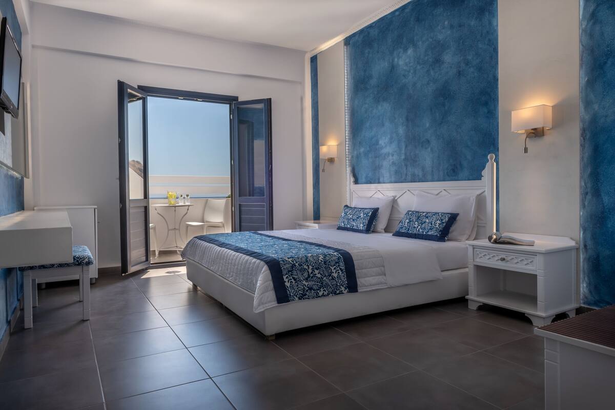 Un dormitorio moderno con una cama grande, una mesita de noche y vistas al exterior a través de una puerta abierta.