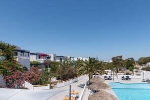 A resort with a swimming pool, white buildings, and palm trees.