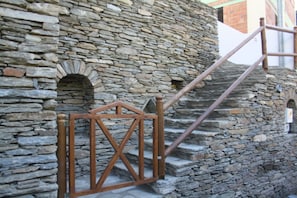 A stone staircase with a wooden handrail and metal gate.