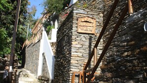 A stone building with a sign for 'Amoray Studios Room Toilet'. - Amorani Studios (Andros)