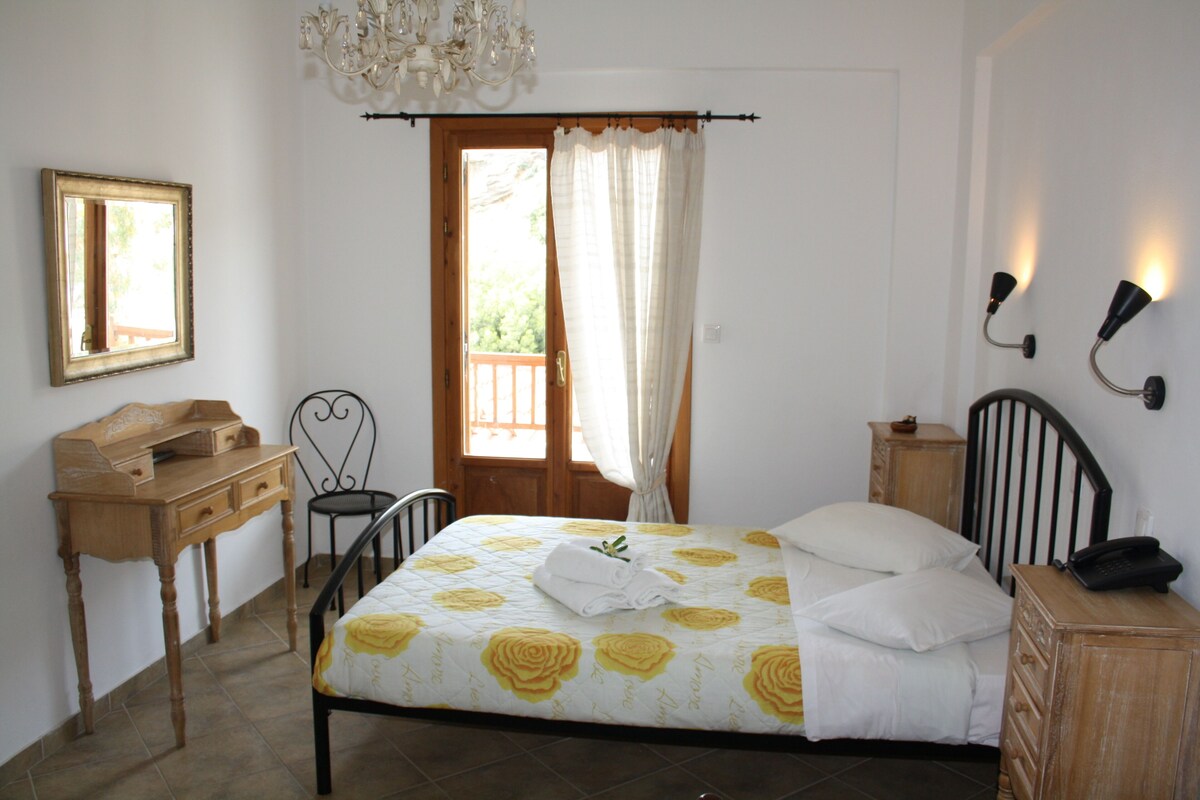 Un dormitorio con cama, escritorio, silla, armario, espejo y ventana con cortinas.