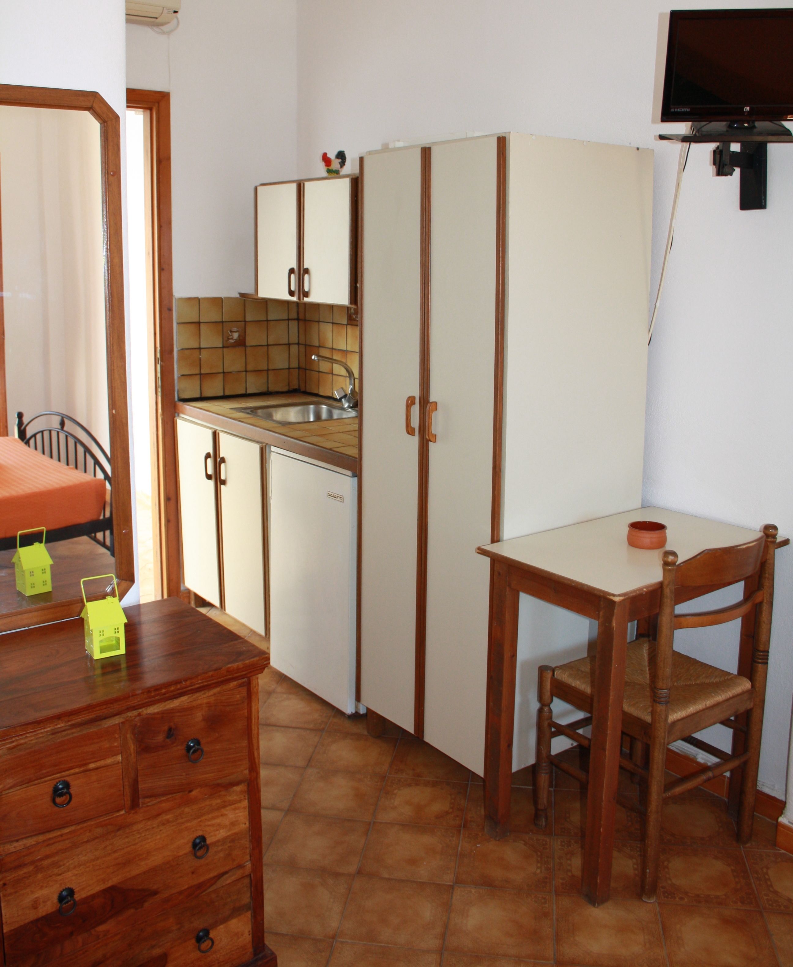 A compact kitchen with a sink, cabinets, and a small table with a chair.