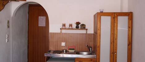 A compact kitchen with a refrigerator, a sink, and a wooden cabinet.