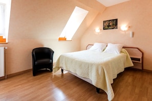 Une chambre à coucher avec un lit, une chaise, un radiateur et une lucarne.