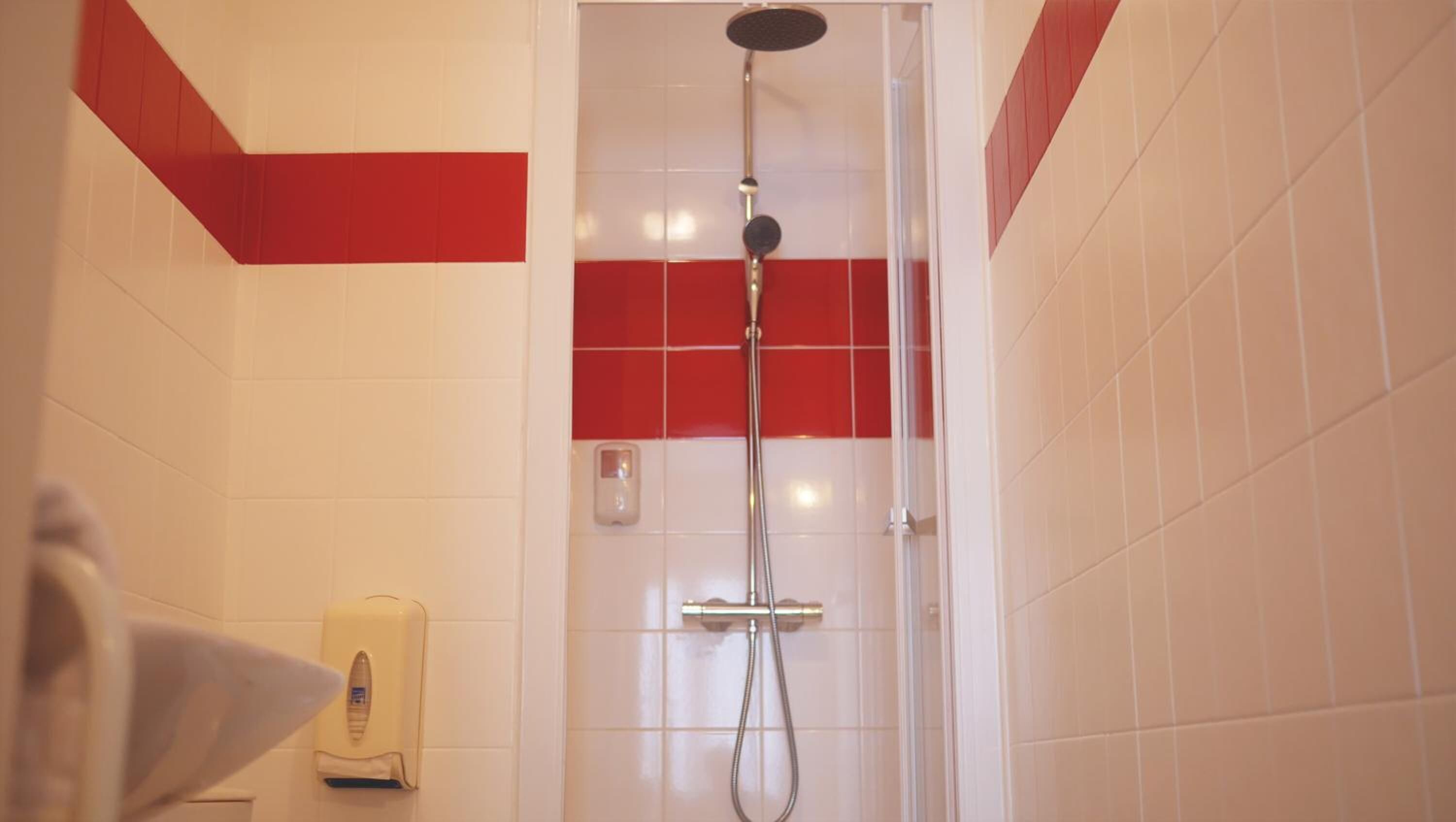 A shower with a handheld showerhead and a wall-mounted control panel.