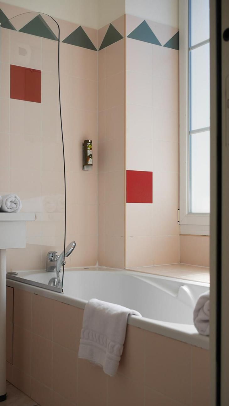 Ein Badezimmer mit Badewanne, Handtuchhalter und einem Fenster.