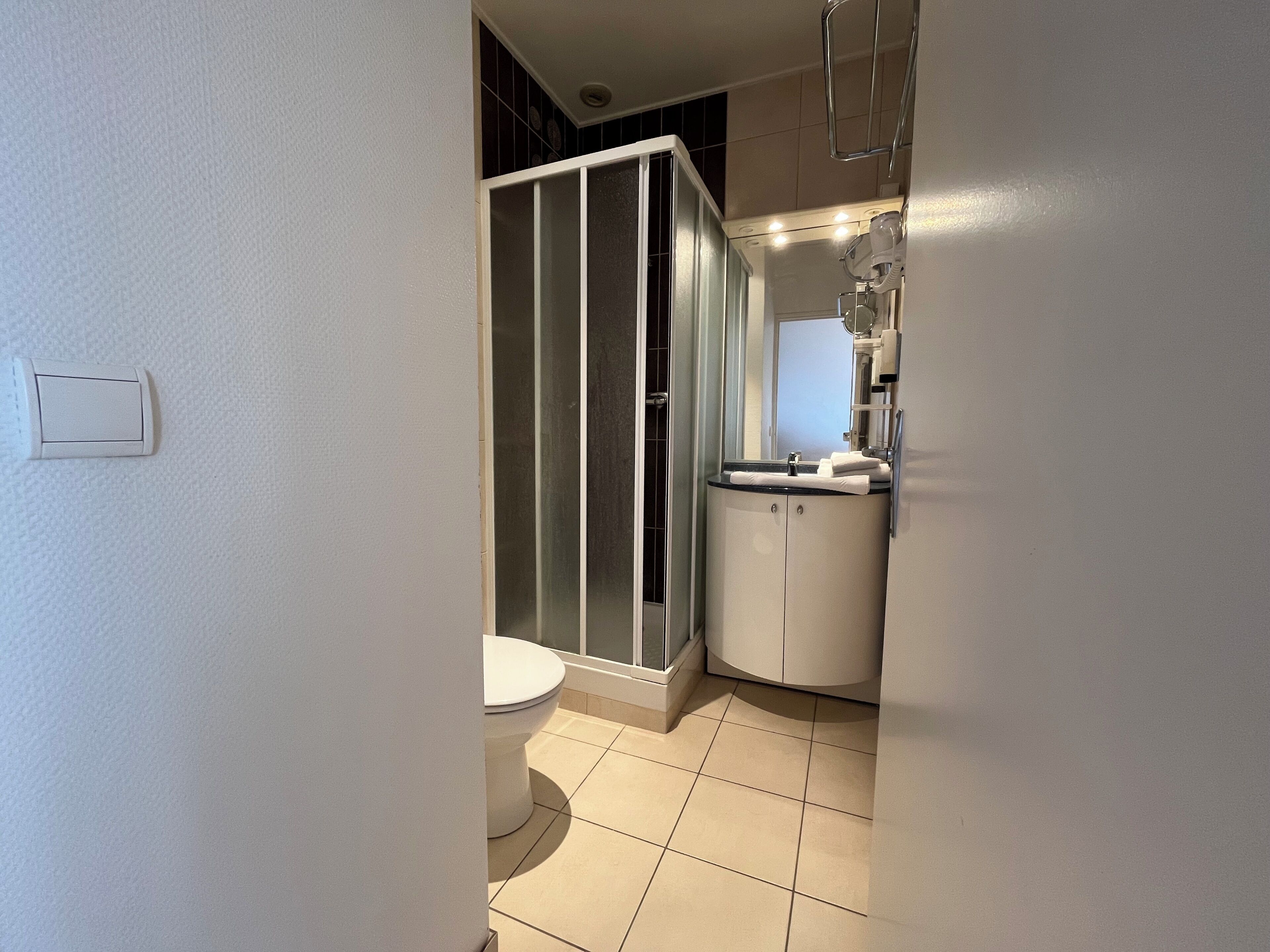 Ein Badezimmer mit Toilette, Duschkabine und Waschbecken mit Spiegel.