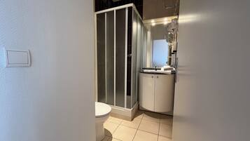 Un baño con inodoro, cabina de ducha y lavamanos con espejo.