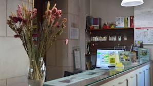 Een receptiebalie met een computer, informatie brochures en een bloemenvaas.