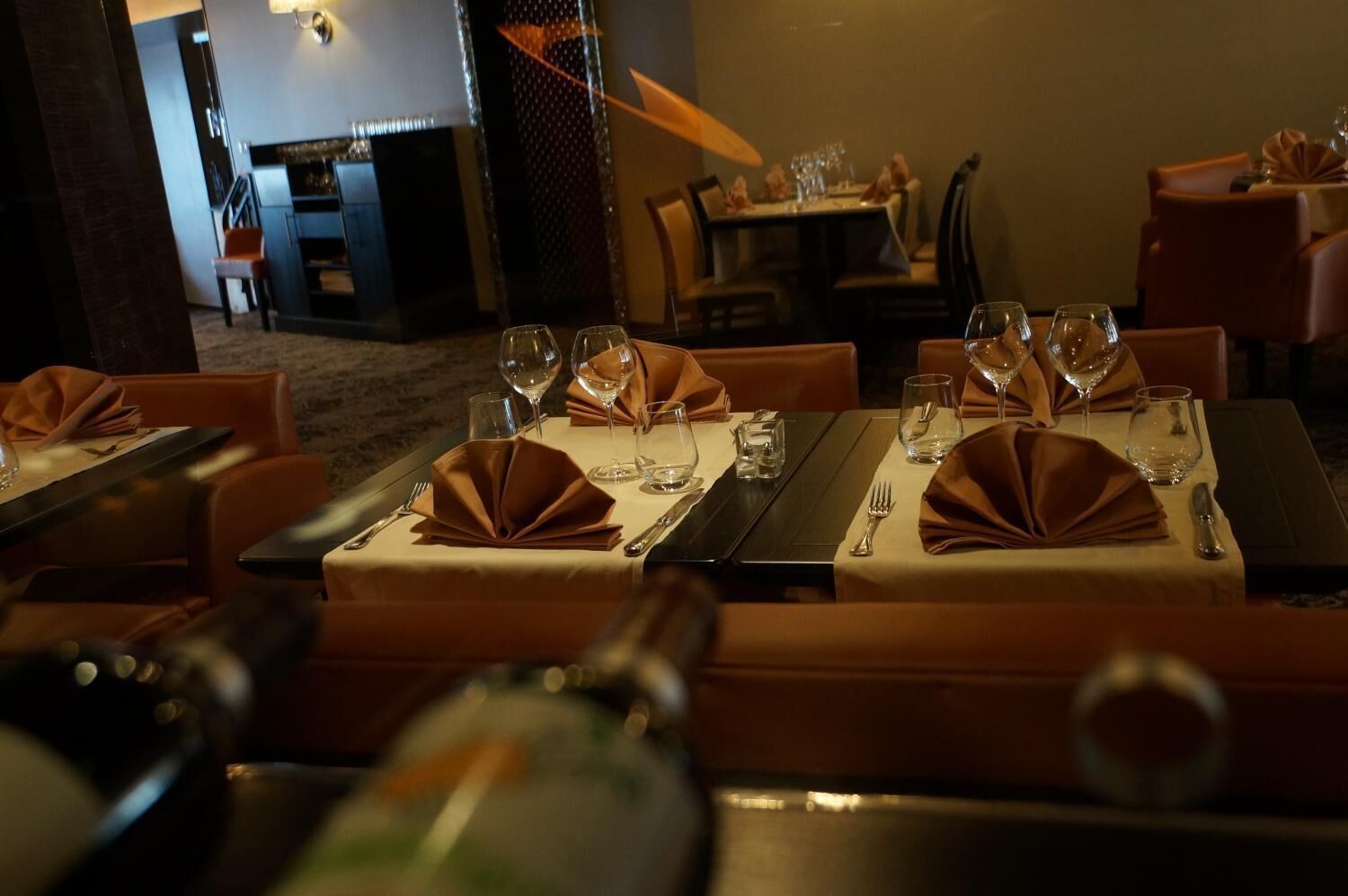 A restaurant with tables set for dining, each with a folded napkin, wine glasses, and cutlery.