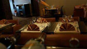 A restaurant with tables set for dining, each with a folded napkin, wine glasses, and cutlery.