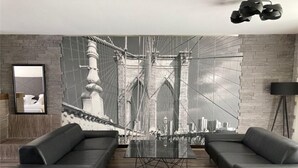 Ein modernes Wohnzimmer mit einem großen Schwarz-Weiß-Foto einer Brücke, zwei schwarzen Sofas, einem Glastisch und einer schwarzen Stehlampe.