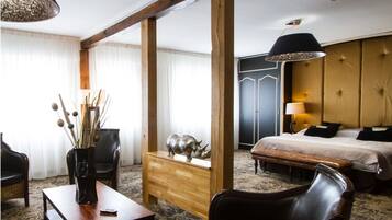 Una habitación de hotel con una cama, un tocador de madera, una silla de mimbre, una mesa de centro y un escritorio.