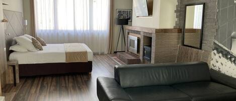 Una habitación de hotel moderna con una cama, un sofá, una chimenea y un televisor.