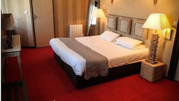 Ein Hotelzimmer mit einem großen Bett, zwei Nachttischlampen, einem Schreibtisch mit Stuhl und einem roten Teppich.