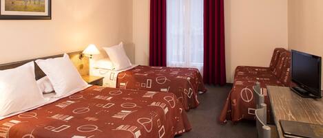 A hotel room with two beds, a desk with a television, and a window with red curtains.
