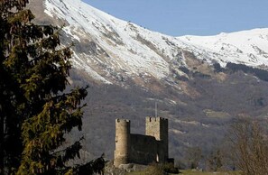 A castle with two towers, surrounded by snow-covered mountains and sparse vegetation. - Le Montaigu (Esquieze-Sere)