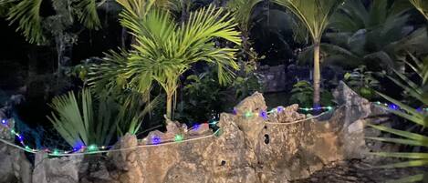 A stone wall with palm trees and decorative lights.