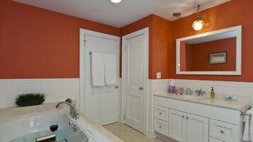 A bathroom with a bathtub, white vanity, and a mirror.