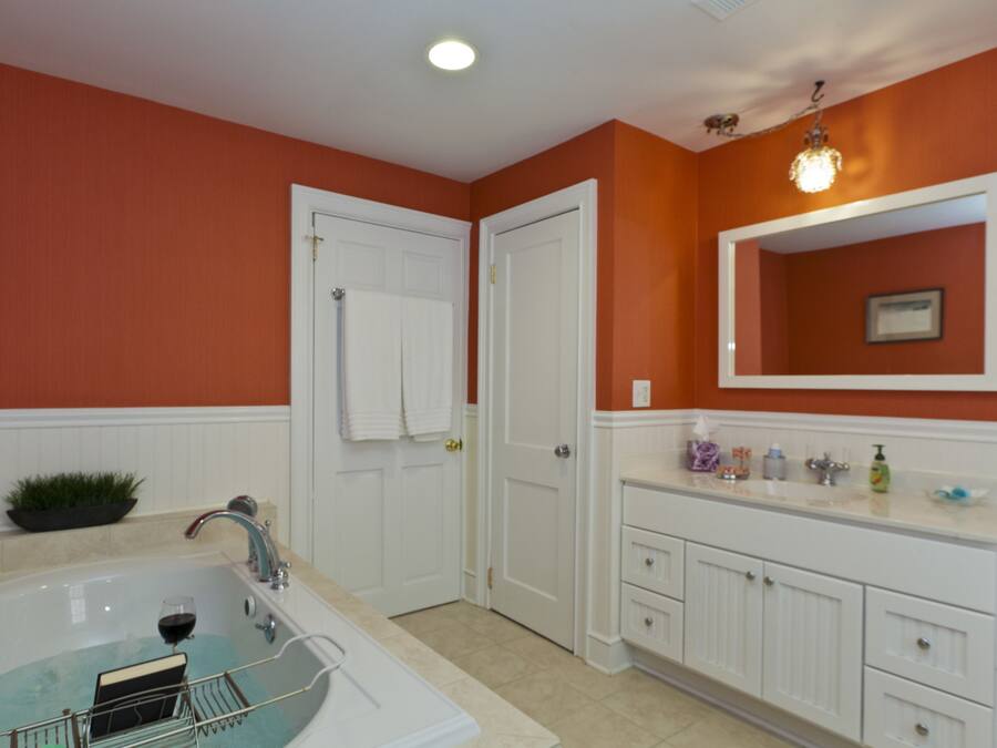 A bathroom with a bathtub, white vanity, and a mirror.