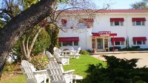 A building with a red awning and a sign that reads "OFFICE". There are white chairs and a table in the front yard. - Holiday Music Motel (Sturgeon Bay)