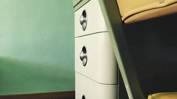 A room with a green wall, a white chest of drawers, and a yellow chair.