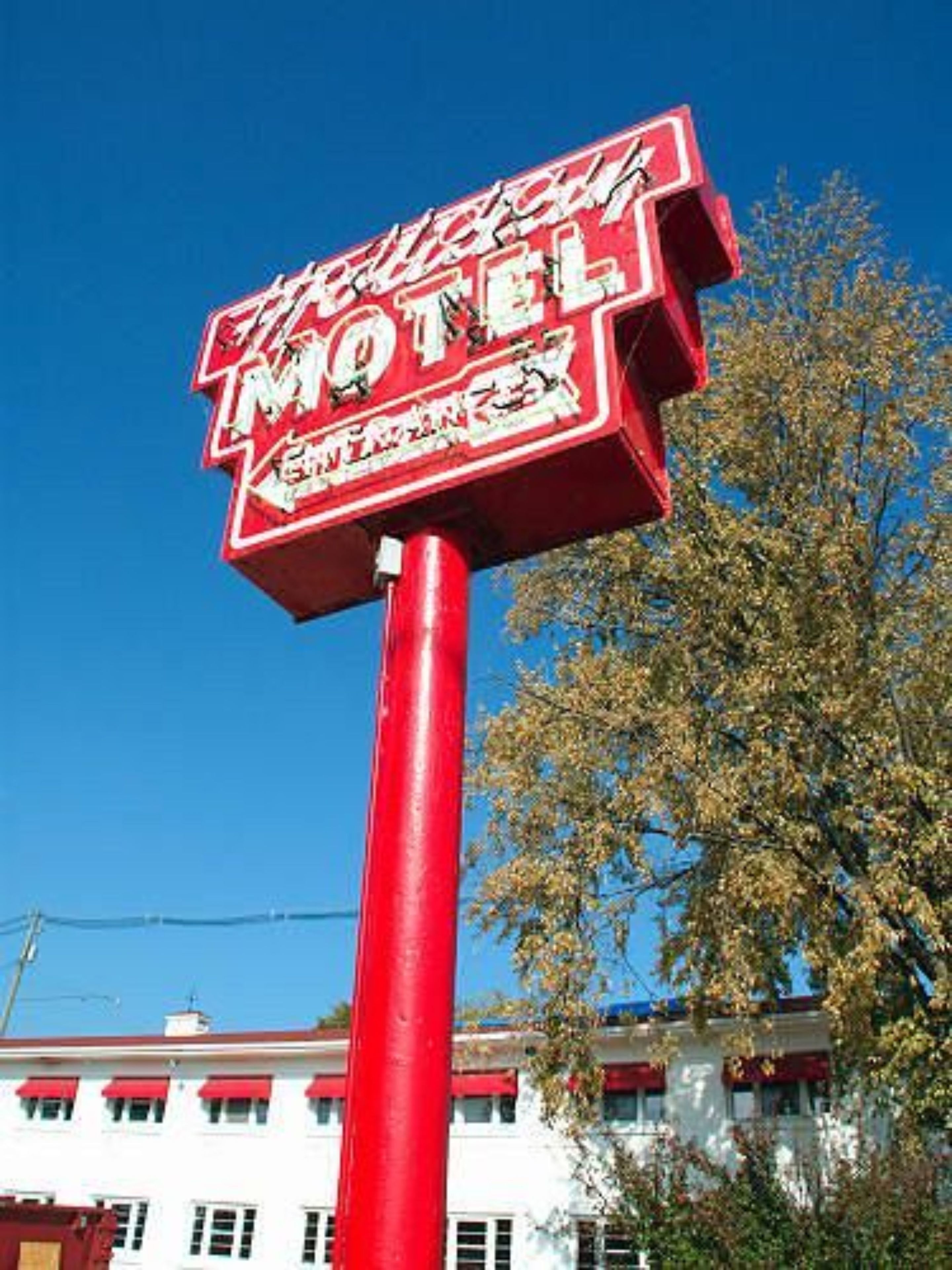 A red motel sign with white lettering against a clear blue sky.
