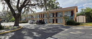 A motel with a two-story structure, a parking lot, and a small adjacent building. - Travelers Inn (Gainesville)