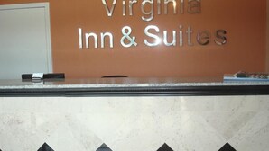Un comptoir d’accueil avec une enseigne indiquant « Virginia Inn & Suites », le tout sur un mur orange.