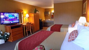 Une chambre d’hôtel avec deux lits, une télévision, un bureau, une chaise, une petite kitchenette et une salle de bain.