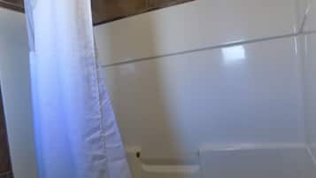 Een badkamer met een bad, douche en toilet.