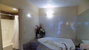 Une salle de bain avec une baignoire sur pieds, un espace douche et un carrelage au sol.