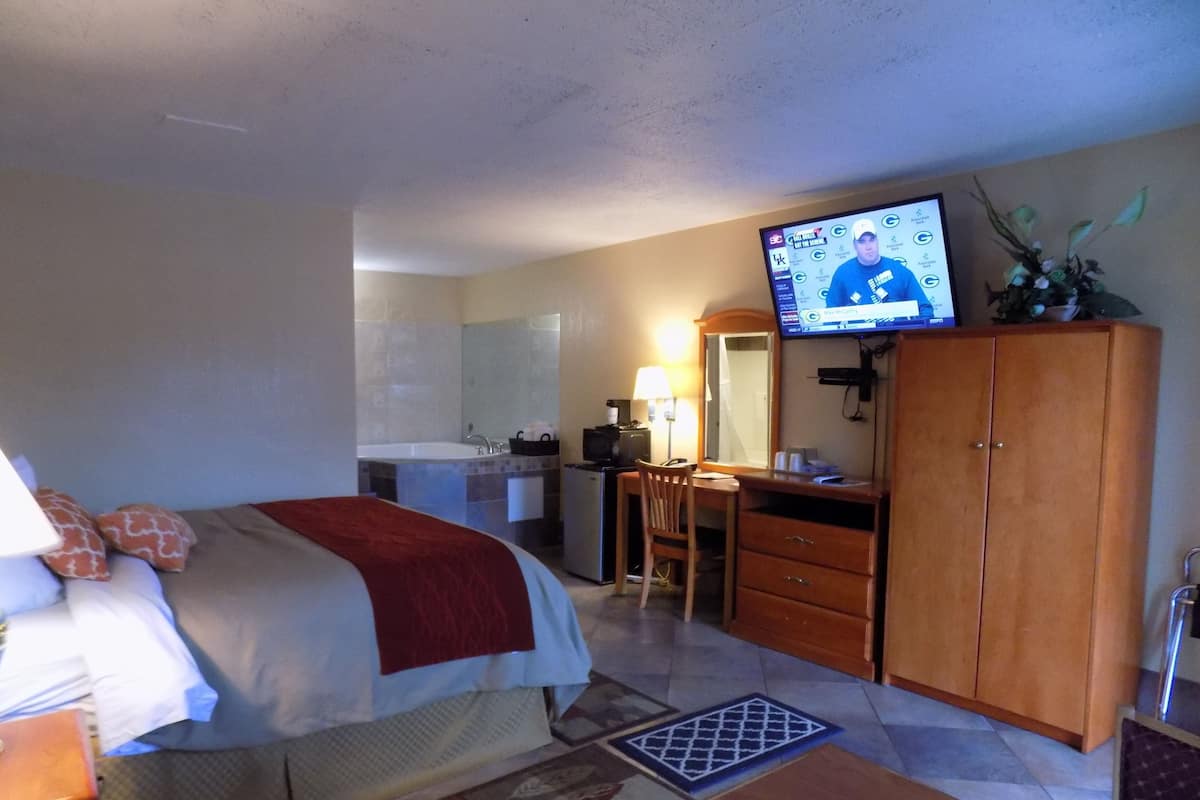 A hotel room with a bed, a desk, a television, a wardrobe, and a bathroom.