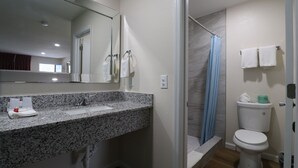 Un baño moderno con encimera de granito, cabina de ducha de vidrio y retrete.