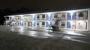 A motel with multiple rooms, a covered parking area, and a staircase leading to the upper level.
