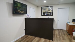 Zona de recepción de un hotel con un separador oscuro, un televisor de pantalla plana y un cartel del Royal Inn.