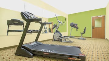 A gym with treadmills, stationary bikes, and a bench.