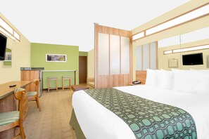 A hotel room with a bed, a desk with chairs, a small kitchenette, and a TV. - Microtel Inn & Suites by Wyndham Tuscumbia/Muscle Shoals (Tuscumbia)
