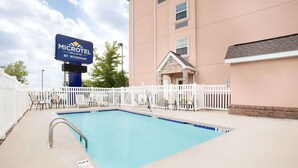 A swimming pool with a white fence, lounge chairs, and a sign for the Microtel Inn & Suites by Wyndham.