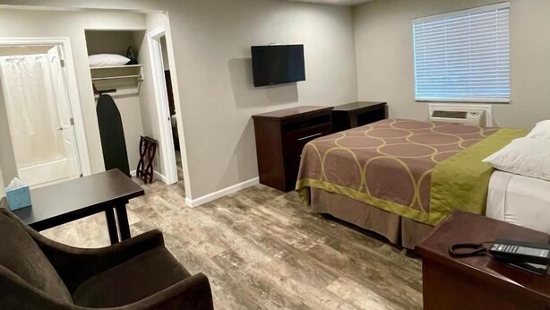 A hotel room with a bed, a desk, a chair, a TV, and a window with blinds. - Budget Lodge Eugene (Eugene)