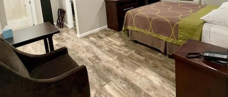 Una habitación de hotel con cama, escritorio, silla, televisor y armario.