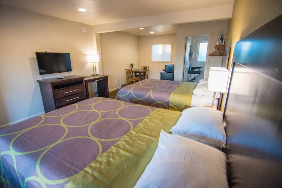 A hotel room with two beds, a TV, a desk, and a chair.