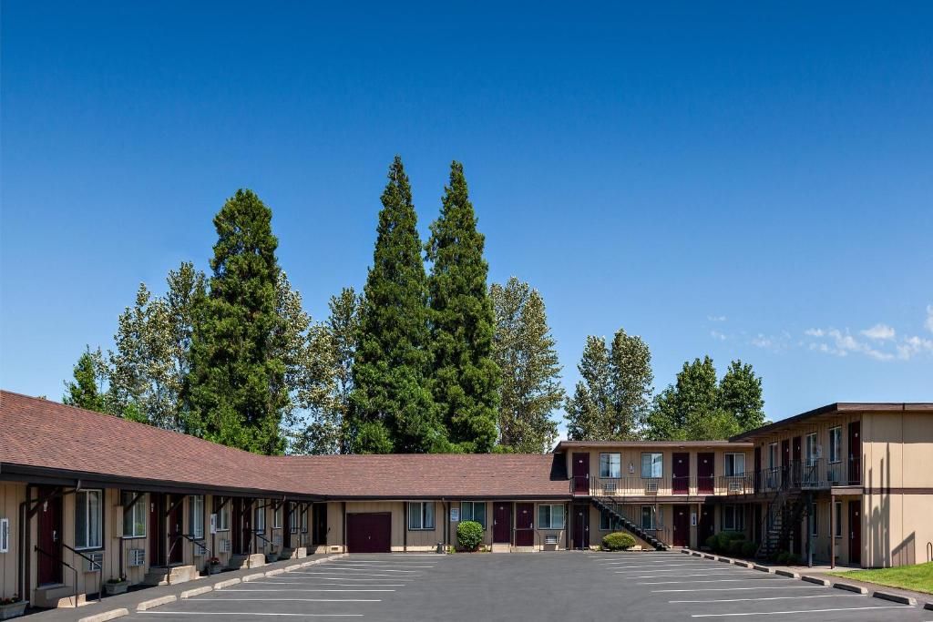 A motel with a parking lot, multiple rooms, and a staircase leading to an upper level.