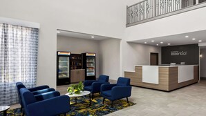 Eine moderne Lobby mit blauen Sitzgelegenheiten, einem Empfangsschalter, Verkaufsautomaten und einer Treppe.