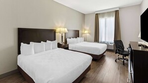 Ein Hotelzimmer mit zwei Betten, einem Schreibtisch, einem Stuhl und einem Fernseher.